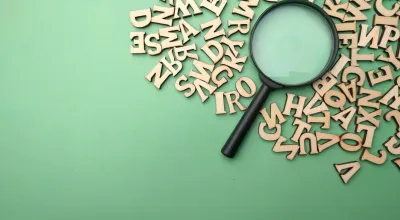 A green backdtop with a magnifying glass surrounded by letters