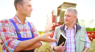 Farmer and loan officer with tablet talking on the farm 
