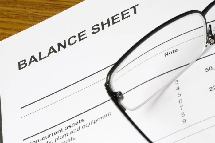 The top left corner of a balance sheet with a pair of glasses laying on top of the paper