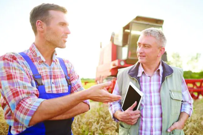 Farmer and loan officer with tablet talking on the farm 